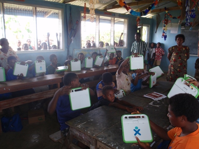 Drekikir Primary Schoolchildren with the new XOs. Village residents, adults and children peering in the windows to see the XOs.